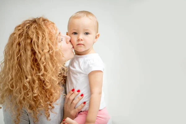 Ingefära kvinna kysser sin bedårande baby på kinden — Stockfoto