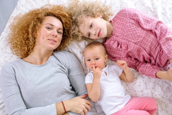 Mutlu bir anne ve çocuklarının yataktaki portresi. — Stok fotoğraf