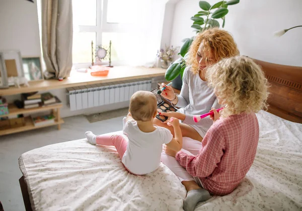 Happy mother playing with her little children with cosmetics — Stock Photo, Image