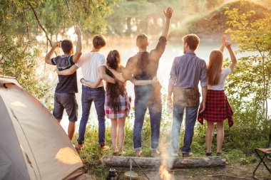 Kollarını kaldırmış mutlu yürüyüşçüler doğanın güzelliğinin tadını çıkarıyorlar.