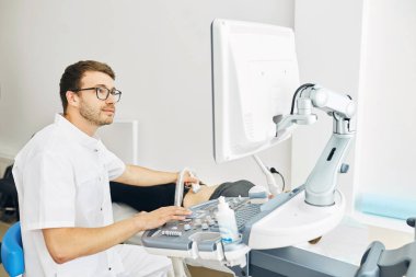 Yakışıklı, yetenekli bir doktor. Ultrason çeviricisini karnında taşıyor.