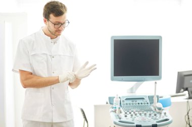 Doktor müşteriyi muayene etmeden önce eldiven takıyor.