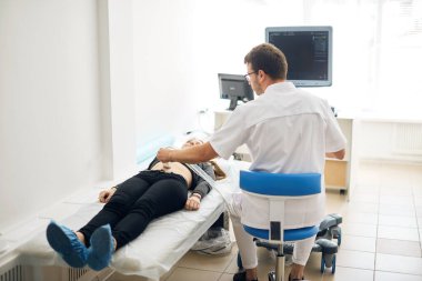 Adam bir kadına ultrason testi yapıyor.