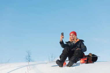 Harika yakışıklı adam karda otururken video çekiyor.