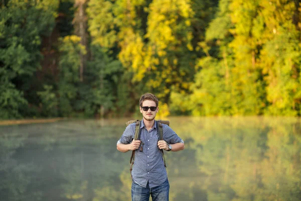 Atraktivní mladý muž v slunečních brýlích pózuje na kameru v nádherné přírodě — Stock fotografie