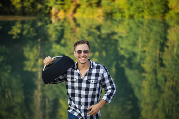 Positive guy is holding a stereo and strolling in the forest — Stock Photo, Image