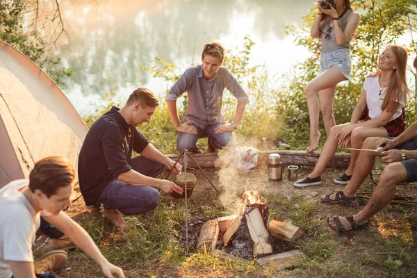 Una compagnia di amici che preparano cibo da campo — Foto Stock