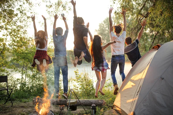 Amis excités sautant sur la rive de la rivière — Photo