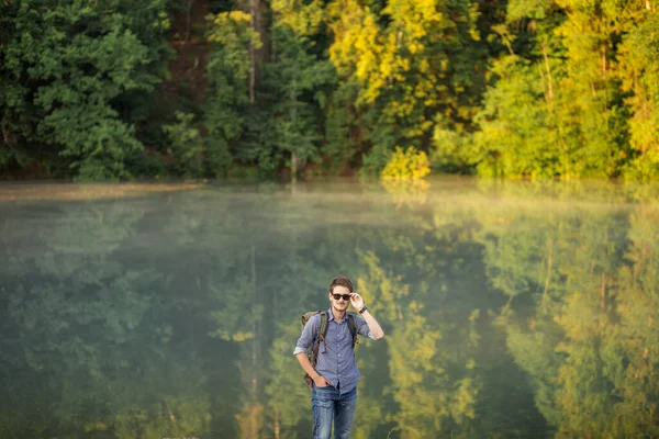 Mladý příjemný rekreant stojí u jezera — Stock fotografie