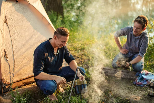 Aantrekkelijke man bereidt een pot voor om het op het kampvuur te zetten — Stockfoto