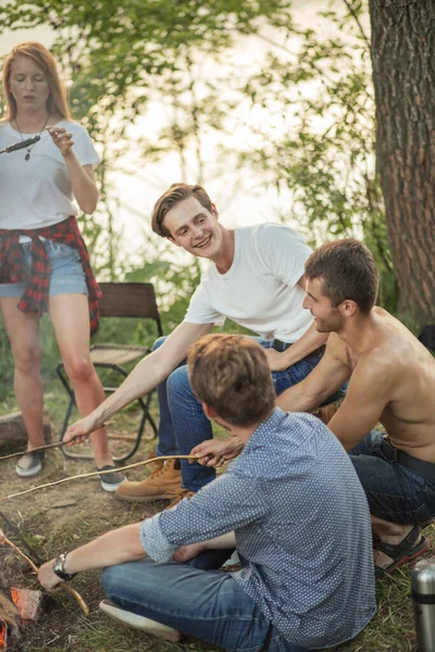 Attractive hikers hilding sticks on the campfire — Stock Photo, Image