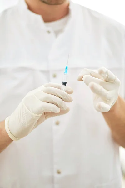 Hombre de uniforme blanco sosteniendo una jeringa en el laboratorio — Foto de Stock