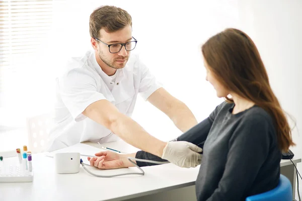 Självsäker begåvad läkare som kontrollerar blodtrycket hos en patient, — Stockfoto