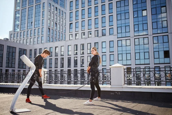 Dois estudantes cansados estão treinando com máquina EMS na rua — Fotografia de Stock