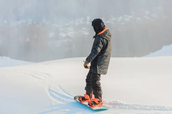 Snowboarder staat op een besneeuwde piek en kijkt naar het prachtige landschap — Stockfoto