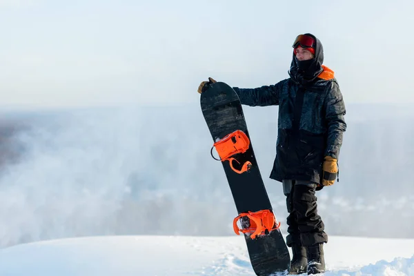 Knappe coole man met snowboard op bergtop. — Stockfoto