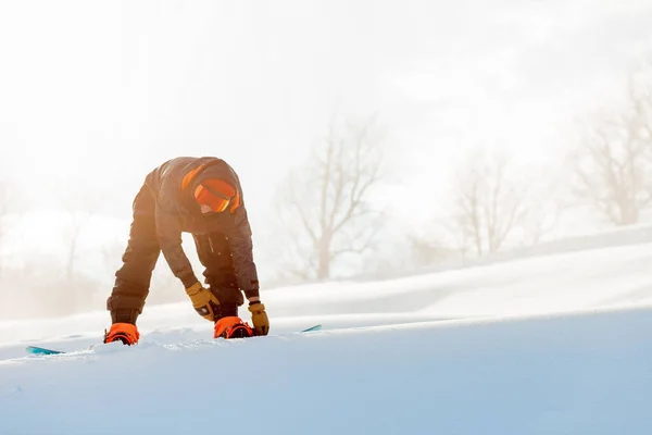 Sportlicher junger Mann schnallt vor dem Wettkampf das Snowboard an — Stockfoto