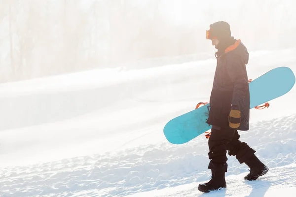 Homem atraente com um snowboard que vai para baixo — Fotografia de Stock