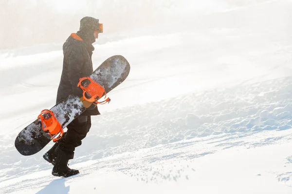 Pensive guy is lopen met een snowboard op een heuvel — Stockfoto