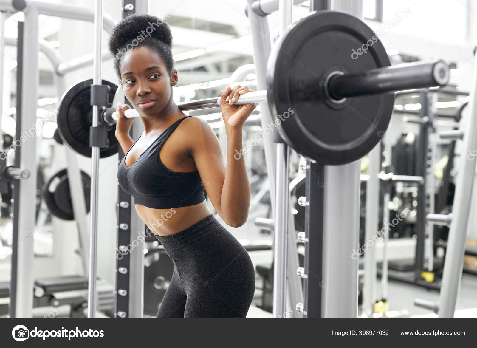 Muscular african female lifting heavy barbell pumping biceps in
