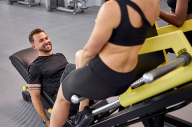 Spor salonundaki atletik insanlar birbirlerini destekliyor, birlikte egzersiz yapıyorlar.