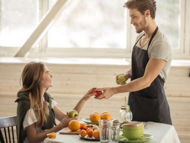 Yakışıklı yakışıklı adam güzel, neşeli bir kıza elma veriyor.