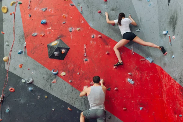 Man and woman competing at rock climbing wall. — Stock Photo, Image