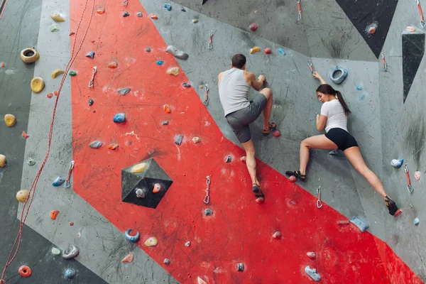Young couple climbing the wall together.