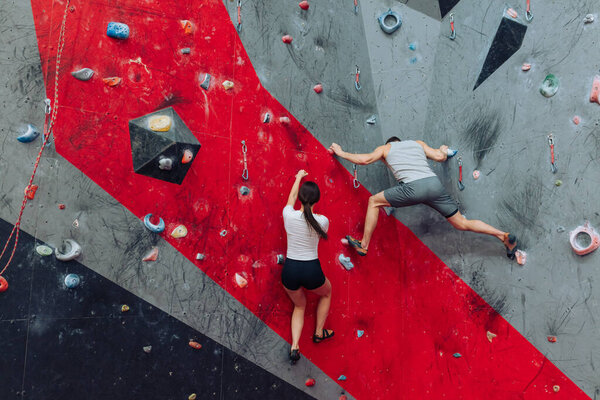 A young man and a woman rock climbing indoors