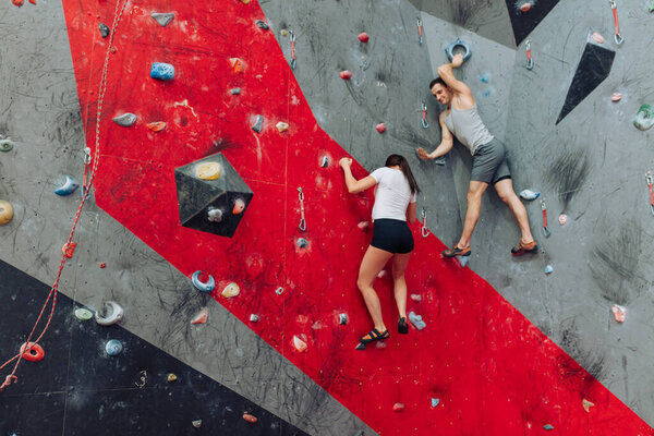 A fit couple training in climbing gym.