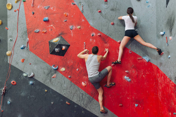 Physically strong man and woman on artificial wall.