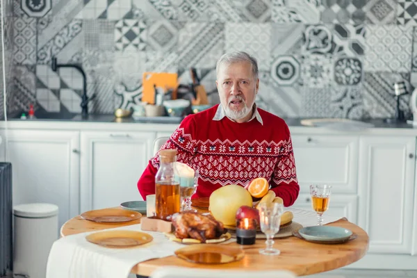 Handsome senior man in red sweater is having dinner alone — Stock Photo, Image