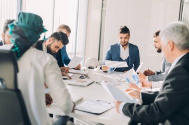 Çok ırklı erkek işletme yöneticileri konferans masasında oturan projeyi tartıştılar