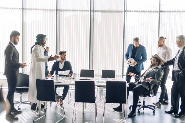 Clientes indianos debatem com empreiteiro árabe sentado contra janela panorâmica — Fotografia de Stock