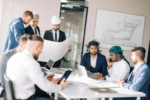 Grupo multirracial de constructores y arquitectos discutiendo el proyecto en la oficina. —  Fotos de Stock