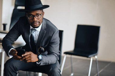 Ofisteki sandalyede dinlenen şık kıyafetli yakışıklı, ciddi bir adam.