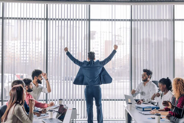 Επιχειρηματίας με τα χέρια ψηλά γιορτάζει τη νίκη του με τους συναδέλφους του χειροκροτούν — Φωτογραφία Αρχείου