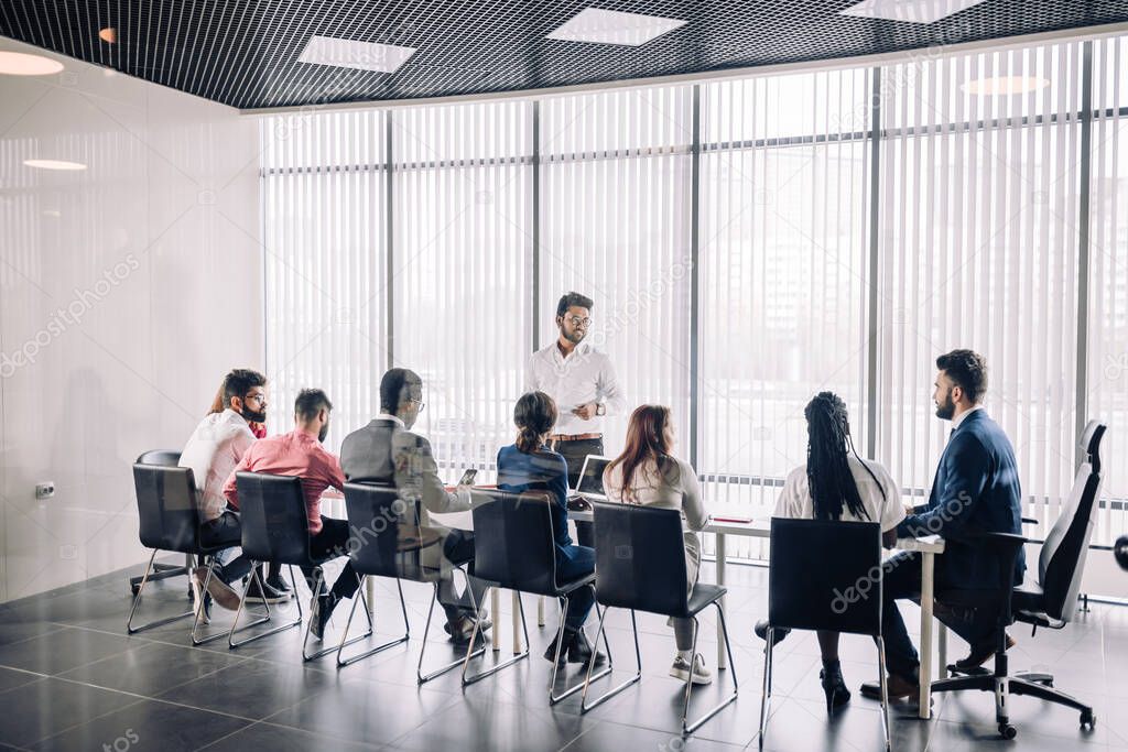 Row of unrecognizable business people sit in conference hall at business event.