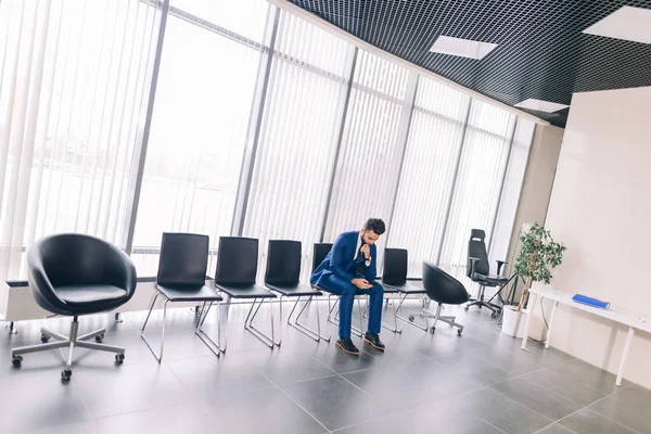 Moda solitária cara elegante sentado na cadeira e usando telefone , — Fotografia de Stock