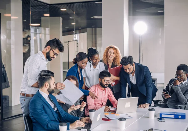 Jovem equipe de trabalho multi-étnico troca ideias em torno de computadores portáteis — Fotografia de Stock