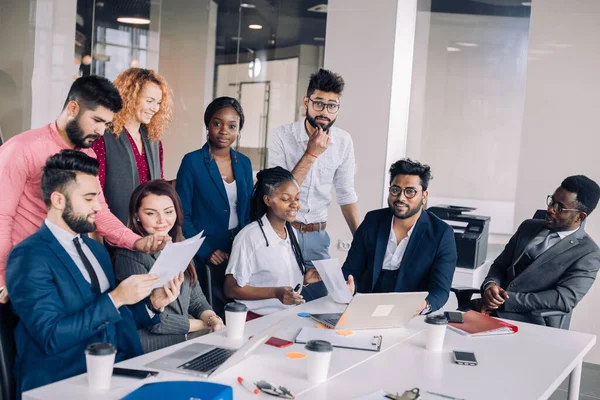 Une jeune équipe de travail multiethnique échange des idées autour d'ordinateurs portables — Photo