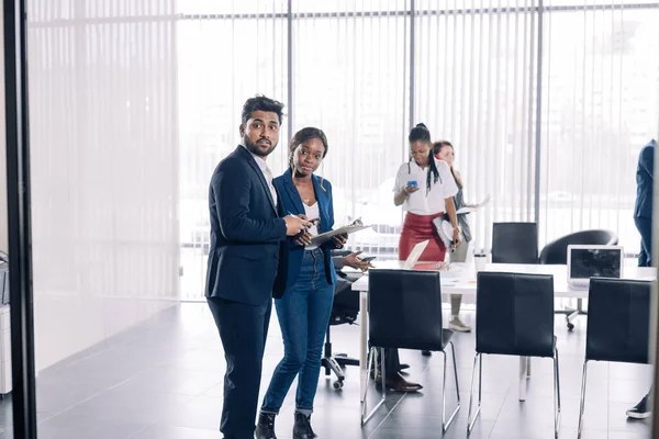 Diversi uomini d'affari sorridenti avendo conversazione in piedi insieme alla riunione. — Foto Stock