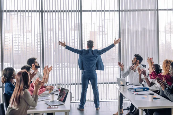 Geschäftsmann mit erhobenen Armen feiert seinen Sieg, während seine Kollegen applaudieren — Stockfoto