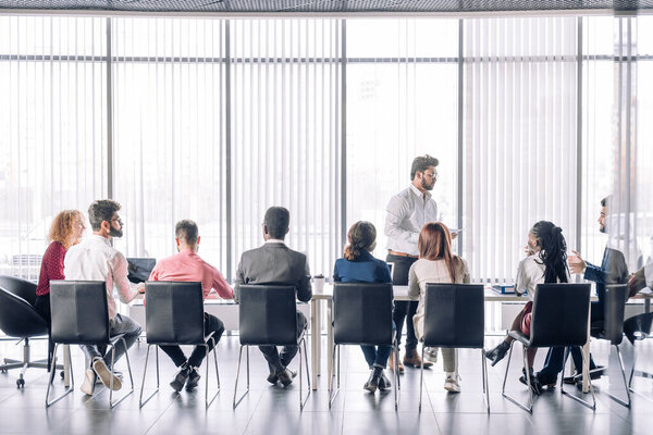 Row of unrecognizable business people sit in conference hall at business event.