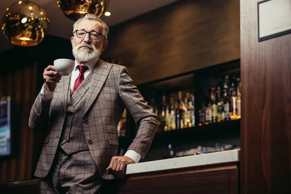 Senior zakenman drinkt koffie in de buurt bar teller in het donker rust — Stockfoto