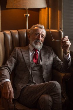 Tatmin olmuş sakallı bir emeklinin evinde dinlenirken gözlük takması..