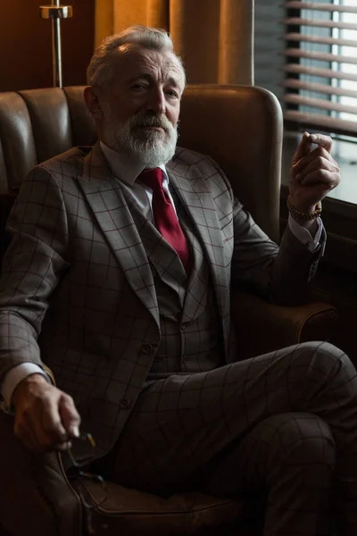 Serene concentrated mature male architector with grey-haired beard smoking cigar — Stock Photo, Image