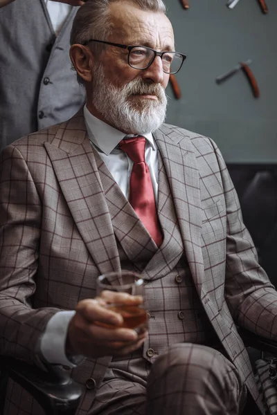 Barbudo viejo hombre de negocios sentado en la peluquería en silla de elegir el diseño de corte de pelo — Foto de Stock