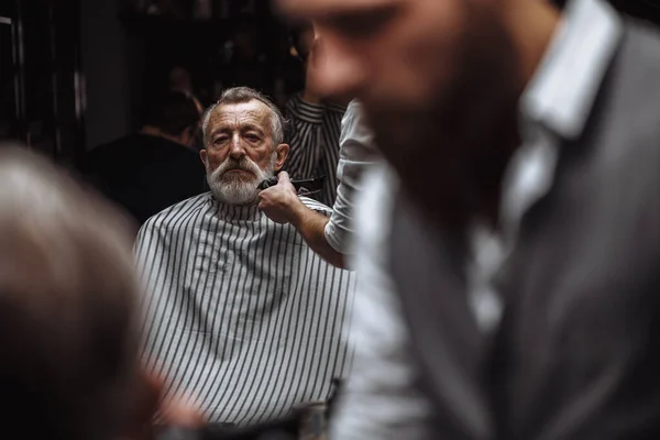 Close up de um cabeleireiro s trabalho para um belo homem velho na barbearia . — Fotografia de Stock