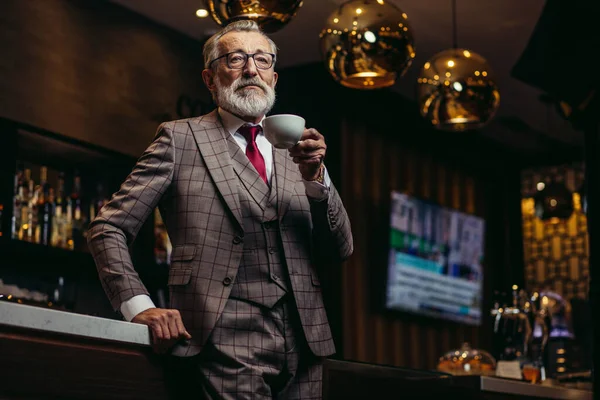 Empresário sênior bebendo café perto do balcão do bar em repouso escuro — Fotografia de Stock